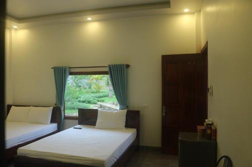 sypialnia z 2 łóżkami i oknem w obiekcie Bungalow VinaHouse w Duong Dong