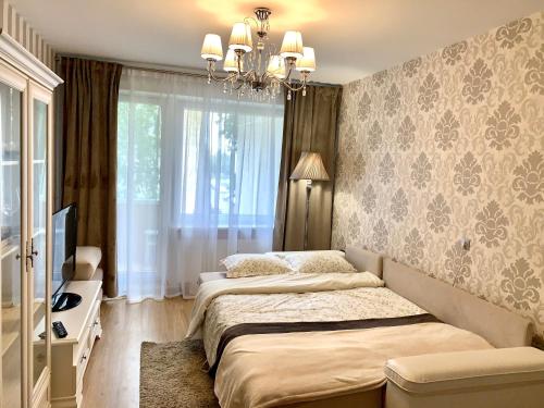 1 dormitorio con 2 camas y lámpara de araña en Venta apartament, en Mažeikiai