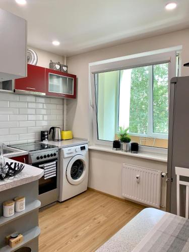 a kitchen with a washing machine and a window at Venta apartament in Mažeikiai