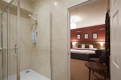 a bathroom with a shower and a bedroom with a bed at Eagle Hotel in Dornoch