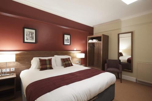 a hotel room with a large bed and a mirror at Eagle Hotel in Dornoch