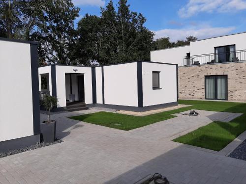a white house with a courtyard with grass at Hotel Restaurant Zum Wacholderhain in Haselünne