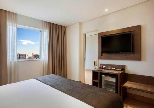 a hotel room with a bed and a flat screen tv at Windsor Brasilia Hotel in Brasilia