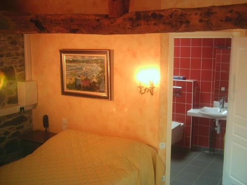 a bedroom with a bed and a bathroom with a sink at Domaine De Kermodest in Quemper-Guézennec