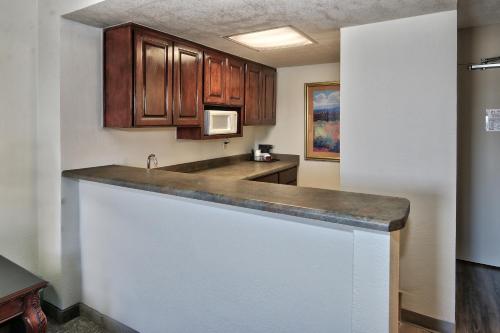 a kitchen with wooden cabinets and a counter top at Ramada by Wyndham Albuquerque Midtown in Albuquerque