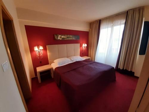 1 dormitorio con cama y pared roja en Hotel Garić, en Garešnica