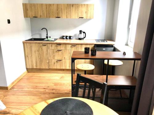 kuchnia z drewnianymi szafkami oraz stołem i krzesłami w obiekcie Apartament Starówka Łagiewniki w Gdańsku