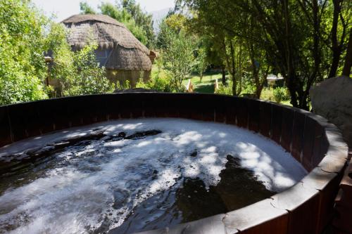 a hot tub in a garden with a hut in the background at Lodge del Maipo in San José de Maipo
