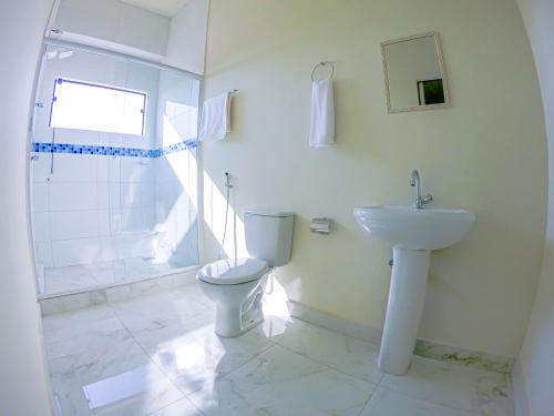 een witte badkamer met een toilet en een wastafel bij HOTEL LAGO ARARAS in Araras