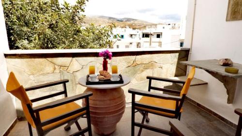 a balcony with a table and two chairs and a window at Virginia Rooms in Tinos