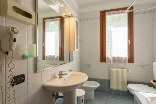 a bathroom with a sink and a toilet and a mirror at Hotel Ristorante al Gabbiano in Ponte di Piave