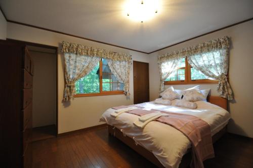 a bedroom with a bed with two pillows and a window at Creek House Hakuba - Vacation STAY 87290 in Hakuba