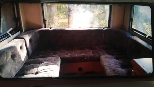 Sofá marrón en una habitación con ventana en Caravane à louer, en Sennecey-le-Grand
