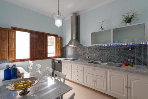 a kitchen with white cabinets and a table with fruit on it at HomeForGuest NEW Duplex with Rooftop next to Arucas Cathedral in Arucas