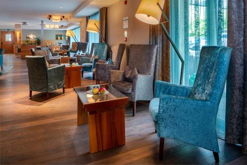 a waiting area in a hotel with chairs and a table at Vitalpina Hotel Waldhof in Rablà