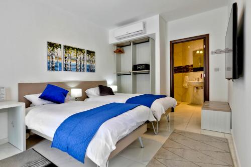 a bedroom with two beds with blue pillows at The Exiles Hotel in Sliema