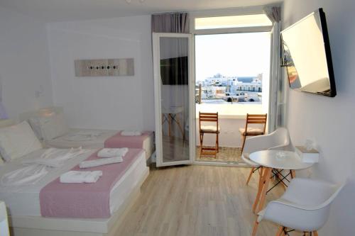 a bedroom with two beds and a table and chairs at Virginia Studios in Tinos
