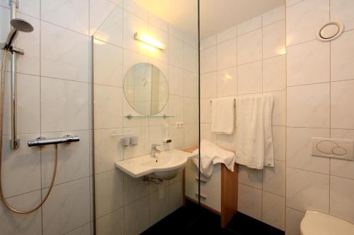 a bathroom with a sink and a shower and a mirror at Hotel Andreas Hofer in Dornbirn