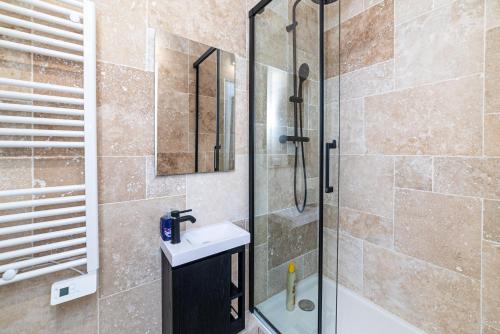 une salle de bain avec une douche avec un lavabo et un miroir dans l'établissement Luxurious Triplex - Marais & Montorgueil, à Paris