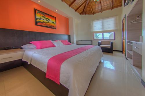 a bedroom with a large bed with an orange wall at Hotel San Vicente Galapagos in Puerto Villamil