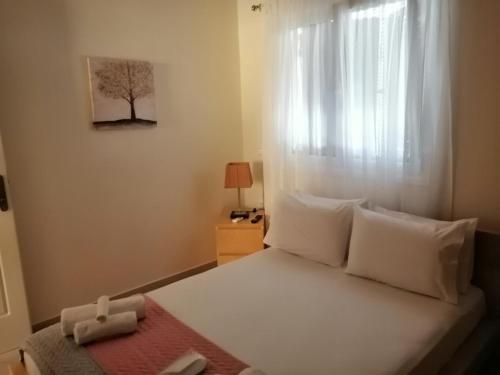 um quarto com uma cama com almofadas brancas e uma janela em Eleni Apartment em Perdika