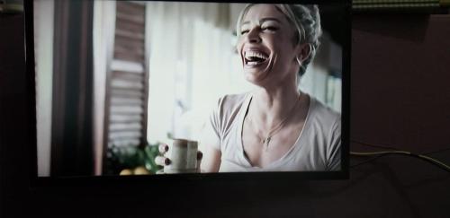 a woman laughing in front of a television screen at Pousada Sírius in São Roque de Minas