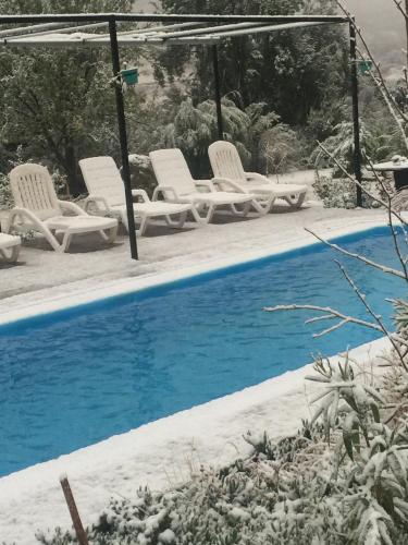 a pool with white chairs and a group at Lodge del Maipo in San José de Maipo