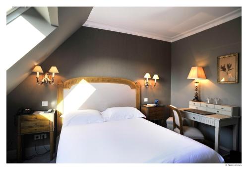 a bedroom with a white bed and a desk and a bed sidx sidx sidx sidx at Hotel De La Treille in Lille