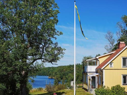 een vlaggenmast voor een geel huis en een meer bij 4 person holiday home in VERUM in Överum