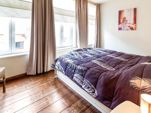 a bedroom with a bed with a purple comforter and two windows at Town house with view over the 3 towers of Bruges in Bruges