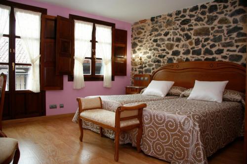 a bedroom with a bed and a chair and windows at Posada Los Gallos in Escalante