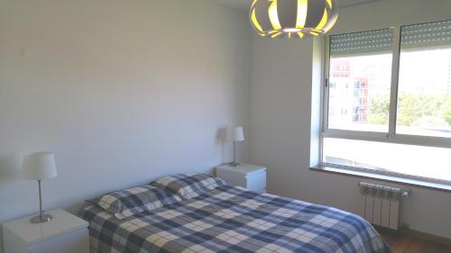 een slaapkamer met een bed met een geruite deken en een raam bij Tagus Life Apartment in Lissabon