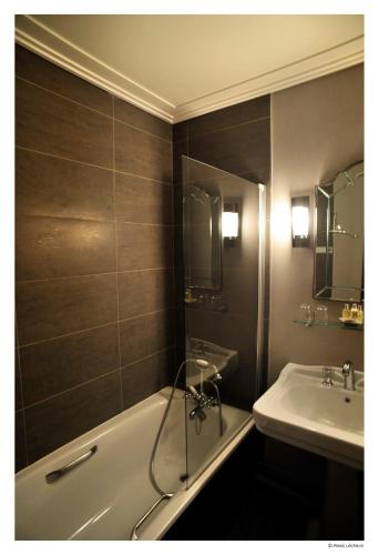 a bathroom with a bath tub and a sink at Hotel De La Treille in Lille