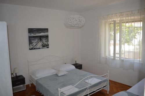 a white bedroom with a bed and a window at Goga Apartments in Primošten