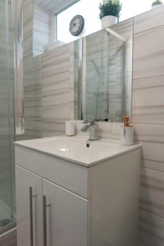 a white bathroom with a sink and a mirror at Gorgeous ground floor apartment + free parking in Manchester