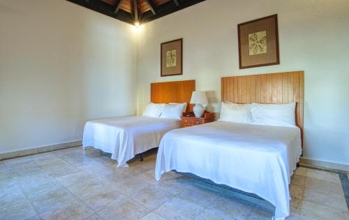 2 Betten in einem Hotelzimmer mit weißer Bettwäsche in der Unterkunft ileverde 82 - Garden villa in Punta Cana