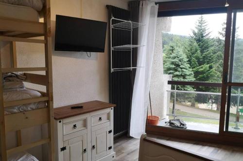 ein Schlafzimmer mit einem Etagenbett, einem TV und einem Fenster in der Unterkunft Le balcon de villard in Villard-de-Lans