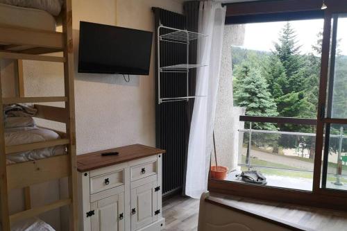 um quarto com um beliche, uma televisão e uma janela em Le balcon de villard em Villard-de-Lans