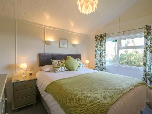 a bedroom with a bed and a window and a chandelier at Smugglers Shack in Polperro