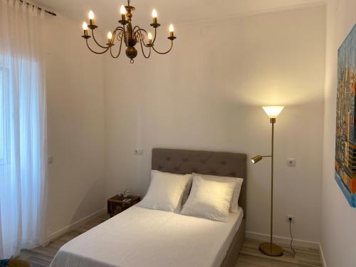 1 dormitorio con cama y lámpara de araña en Casa Laranjeira Olhão, en Olhão