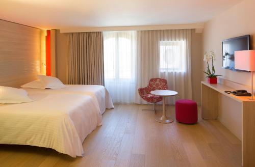a hotel room with a bed and a table and a chair at Hôtel & SPA Oceania L'Univers Tours in Tours