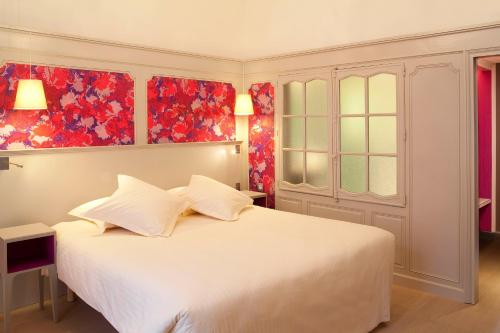 a bedroom with a white bed with two pillows at Hôtel & SPA Oceania L'Univers Tours in Tours