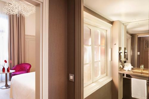 a bedroom with a bed and a sink and a mirror at Hôtel & SPA Oceania L'Univers Tours in Tours