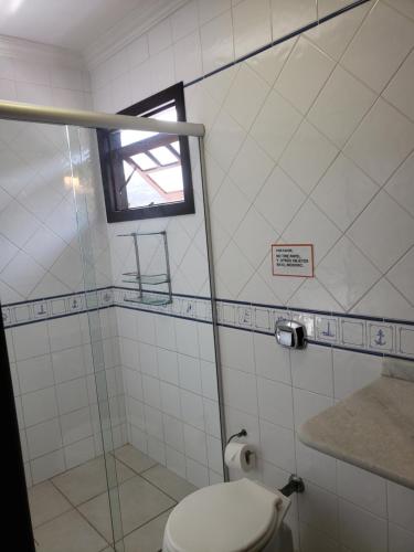a bathroom with a toilet and a window in it at Pousada Pedra da Gaivota in Bombinhas