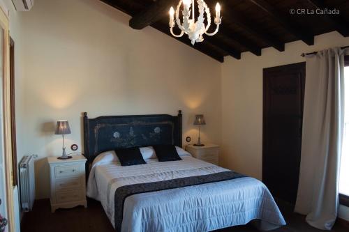 1 dormitorio con cama y lámpara de araña en Casa Rural La Cañada en Aldeanueva del Camino
