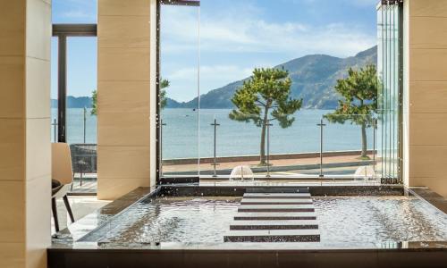 a pool with a view of the water from a building at Stubborn Hotel in Geoje 