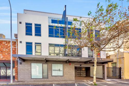 a white building with blue windows and a tree at New Haus by Hougoumont Hotel, former Bannister 22 in Fremantle