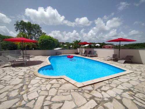 a swimming pool on a patio with umbrellas at Ti Village Creole in Sainte-Anne