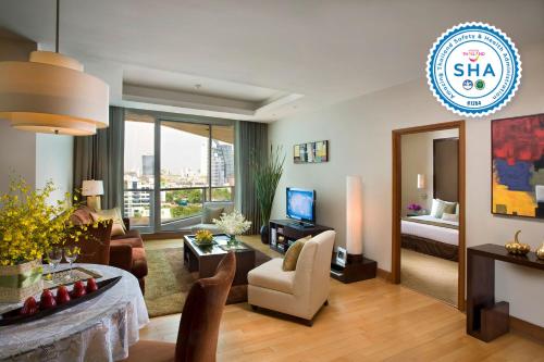a living room filled with furniture and a tv at Ascott Sathorn Bangkok - SHA Plus Certified in Bangkok