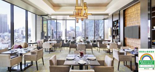 un ristorante con tavoli, sedie e ampie finestre di Oakwood Premier Tokyo a Tokyo